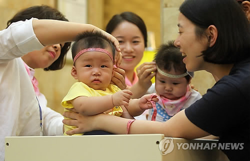 资料图片：2014年7月，“母乳喂养健康宝宝”选拔大赛在大田市一家酒店举行。评委正在给宝宝量头围。（韩联社）