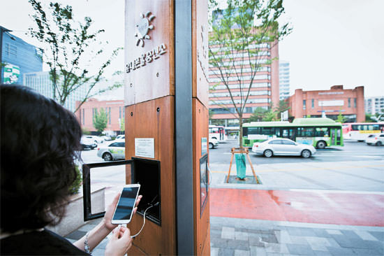 图为一位市民正在松坡区政府的太阳能免费手机充电站为自己的智能手机充电。