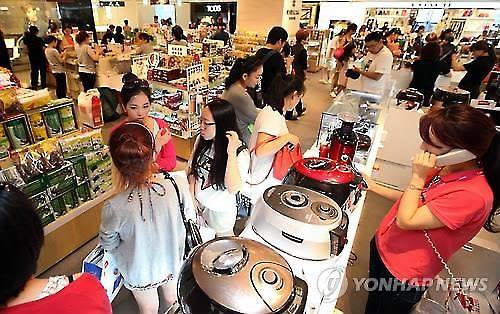资料图片：中国游客们在韩国免税店选购电饭煲。（韩联社）