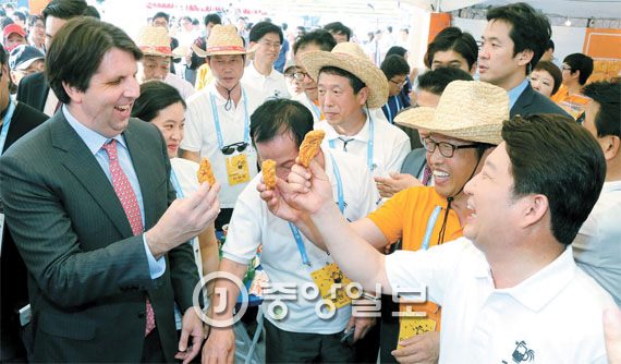 图为美国驻韩大使马克·李柏特（左）去年7月前往在大邱市头流公园会举行的大邱啤酒炸鸡庆典现场与大邱市长权泳臻（右）一起吃炸鸡。（图片来自中央Photo）