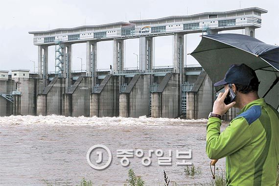图为在朝鲜黄江水库开始泄洪的7月6日，韩国一位居民正在京畿道涟川郡郡南水库观察水位。