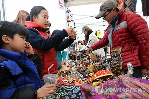资料图片：2014年3月23日，在首尔光化门广场，孩子们在外国人跳蚤市场挑选物品。（韩联社）