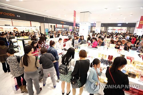 资料图片：中国游客在韩国免税店化妆品柜台前排起长龙。（韩联社）