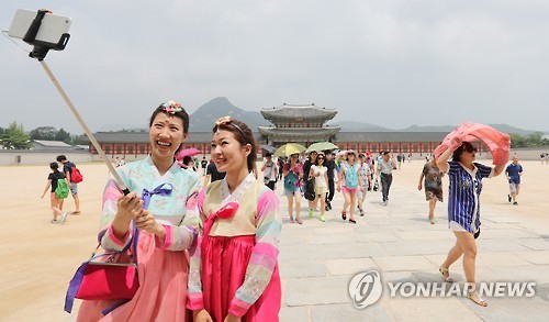 资料图片：2016年7月28日，在景福宫，游客穿着韩国传统服装拍照。（韩联社）