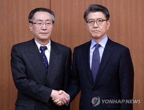 4月10日，在首尔外交部大楼，金烘均（右）与武大伟握手合影。（韩联社）