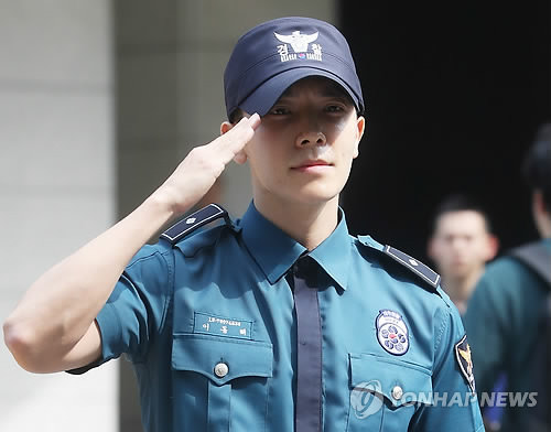 14日上午，在首尔地方警察厅，东海向前来迎接的粉丝们敬军礼。（韩联社）