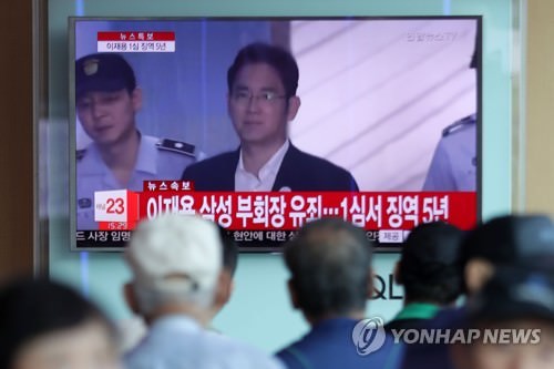 8月25日下午，在首尔站，首尔市民正在围观判决三星副会长李在镕有罪的新闻。（韩联社）