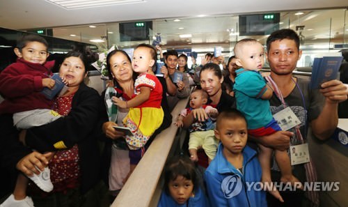 资料图片：7月25日上午，在仁川机场，4户缅甸家庭的23名难民通过边检入境韩国。（韩联社）