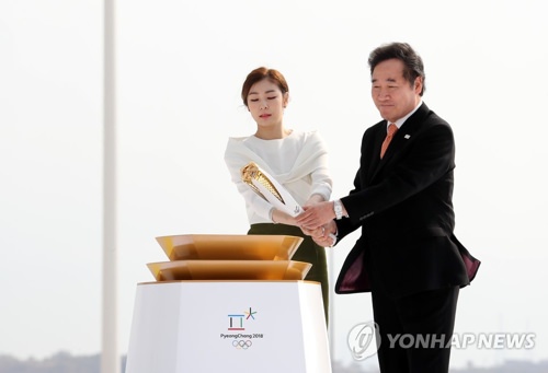 11月1日上午8时30分，运送圣火的专机抵达仁川国际机场。图为平昌冬奥宣传大使金妍儿（左）、国务总理李洛渊用圣火点燃火炬。（韩联社）