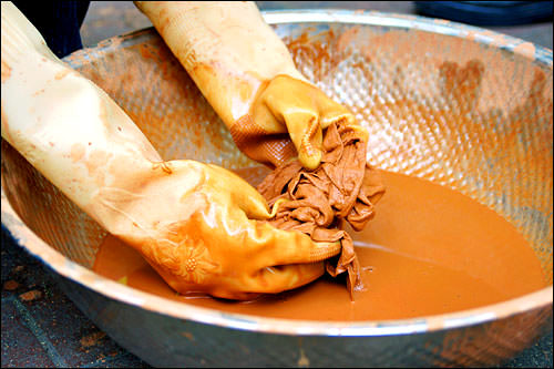 2. 在黄土里放上水和盐,搅拌成液体,放入棉布浸泡10分钟,10分钟后将棉布拿出,用力挤出水分。